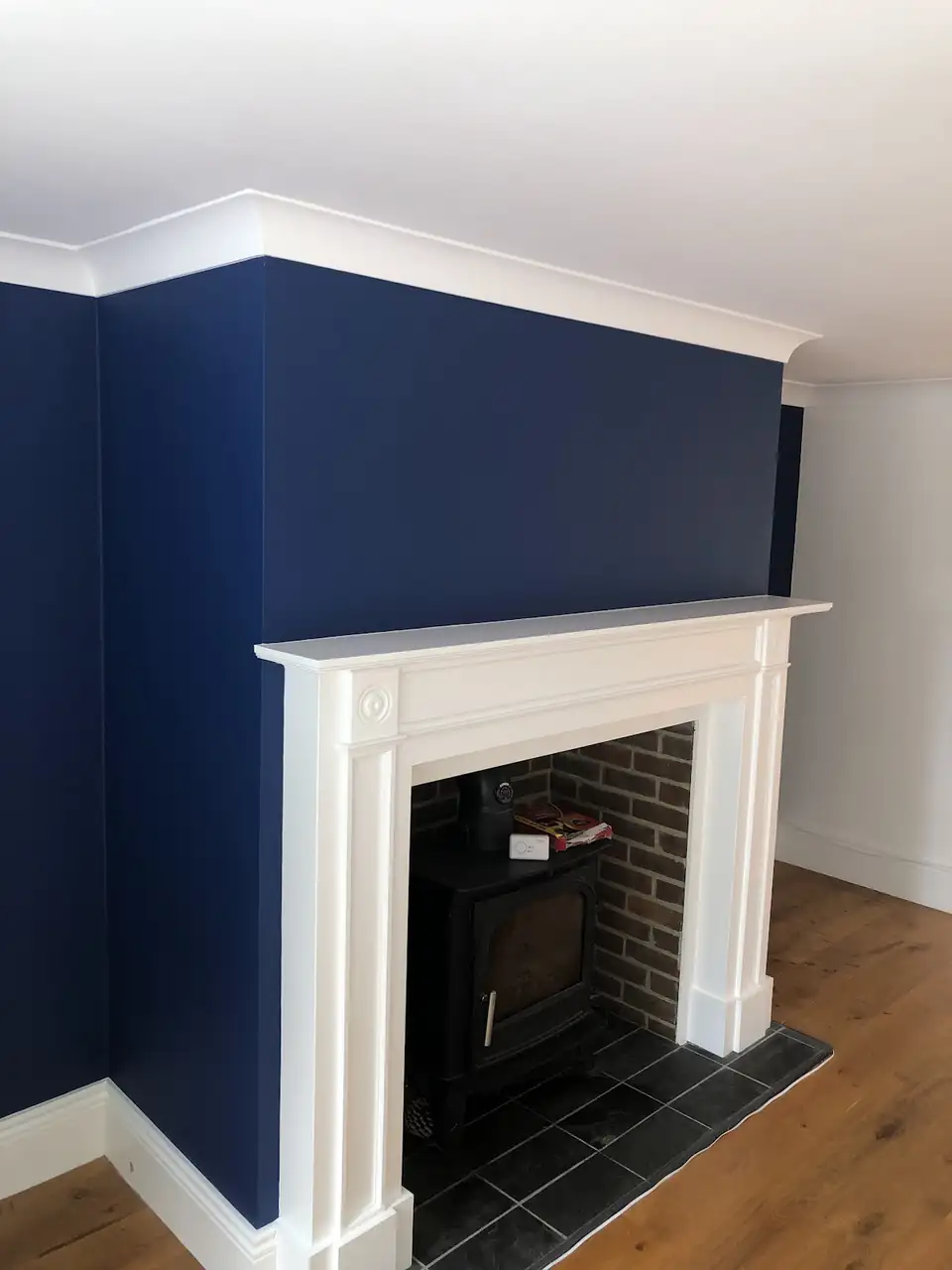 Deep navy chimney breast with a white painted fire surround and coving, decorated by KST Painting & Decorating in Bournemouth