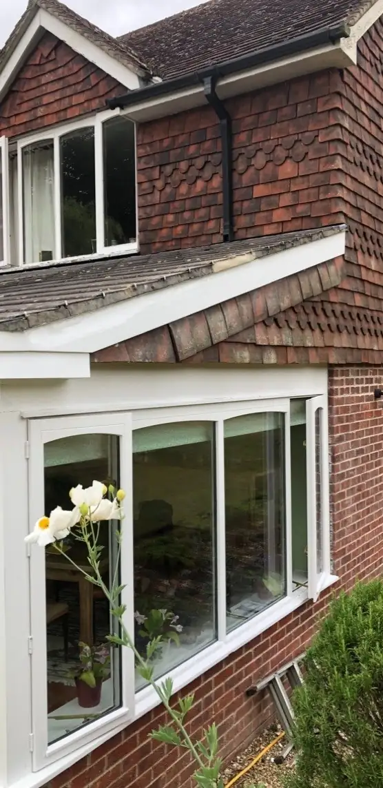 Freshly painted white fascia and window frames on a brick and tile hung house