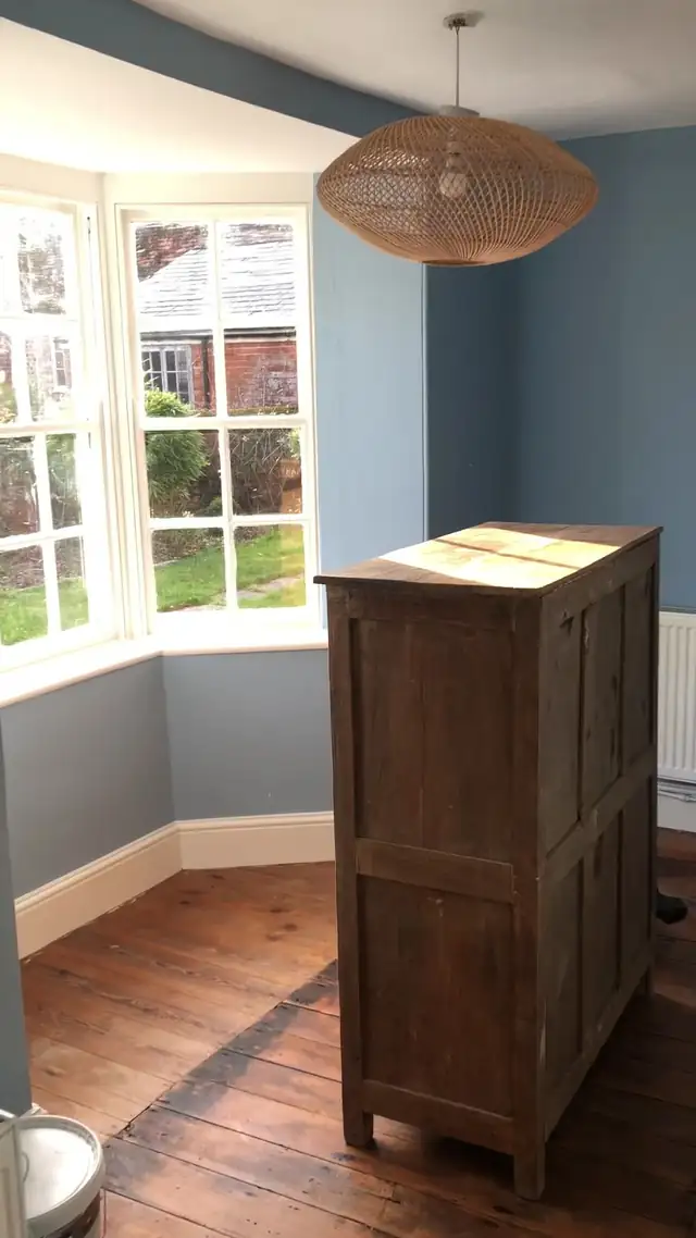 Bay window room painted in soft blue with white skirting and woodwork